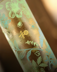 Glass bottle with floral etching on a blurred background