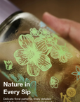 Close-up of a can with floral designs and text about nature in every sip.