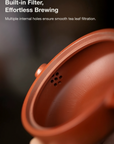 Red ceramic teapot with text about built-in filter and effortless brewing.