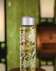 Clear glass bottle with floral design on a wooden stand against a blurred background
