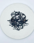 Loose-leaf Honey Orchid DanCong Oolong tea leaves displayed on a white ceramic plate, highlighting the twisted high-mountain Phoenix DanCong leaves.