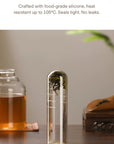 Food-grade silicone lid with a glass tea strainer on a wooden surface.