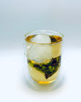 Cold-brew DanCong oolong tea bag steeping in a double-walled glass, highlighting fresh lemon-leaf aromatics.
