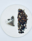 Moonlit Magnolia tea bag and loose DanCong Oolong leaves displayed on a white plate, featuring Yik Lan Hion’s signature magnolia-floral aroma.