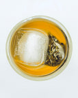 Cold-brewed Silent Jasmine DanCong Oolong tea bag floating with ice in a clear glass cup, top-down view.