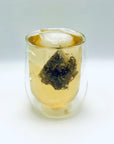 Cold-brew glass showing a blooming Silent Jasmine DanCong Oolong tea bag infusing in chilled water.