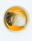 Top view of Jaktea Silken Orchid Dancong Oolong cold brew, showing the pyramid tea bag steeping with visible orchid-aroma tea leaves and ice.