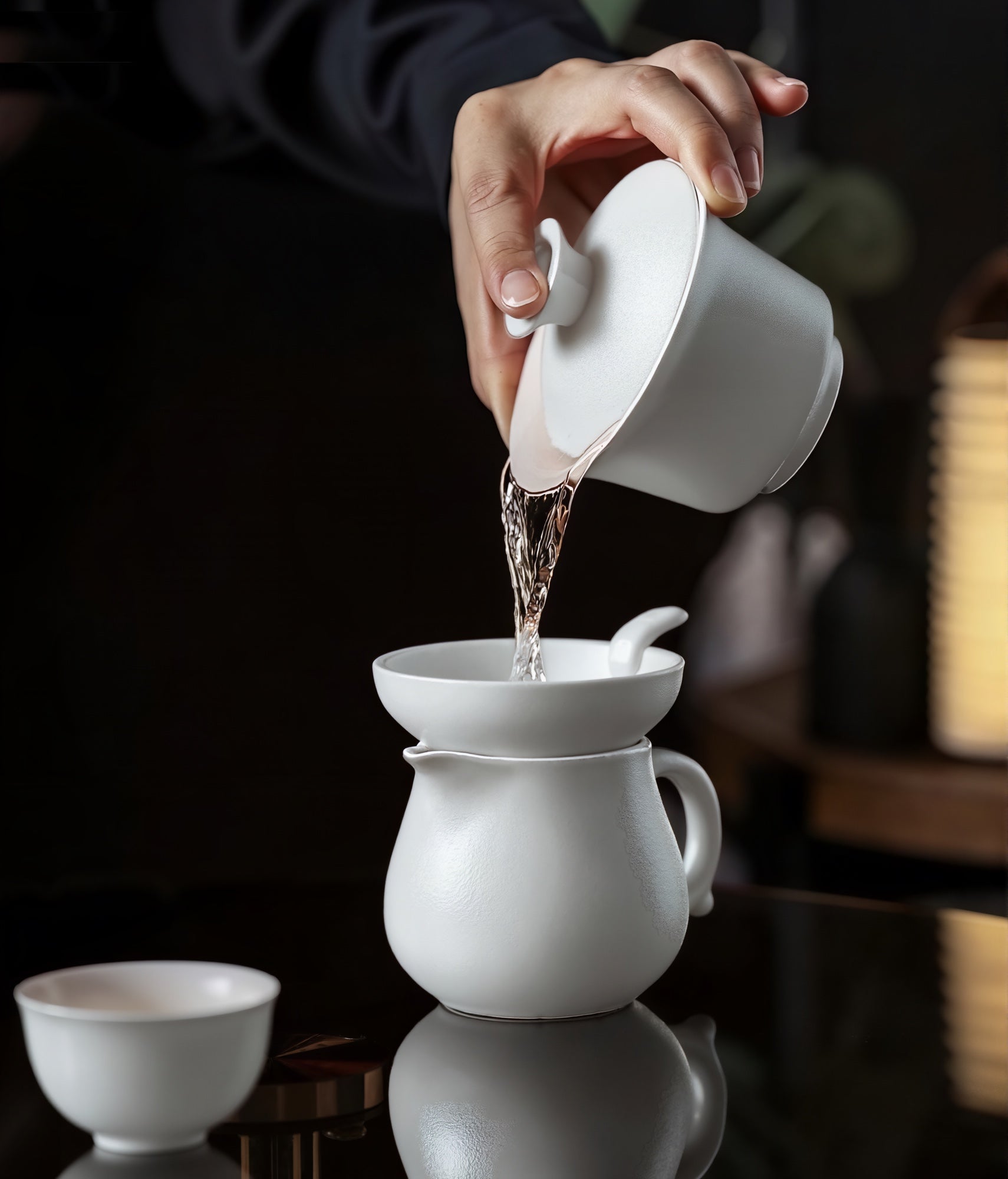 Pouring golden oolong from a white gaiwan into a fairness pitcher — a serene moment of Gongfu tea ritual, captured in refined elegance. Jaktea Dancong Oolong 
