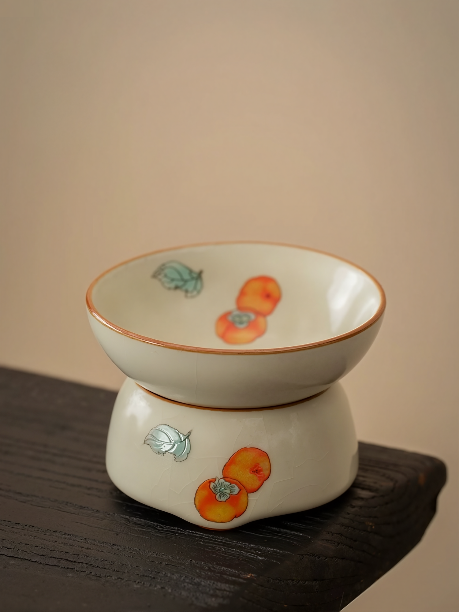 Porcelain tea strainer with hand-painted persimmon design, placed on a wooden surface