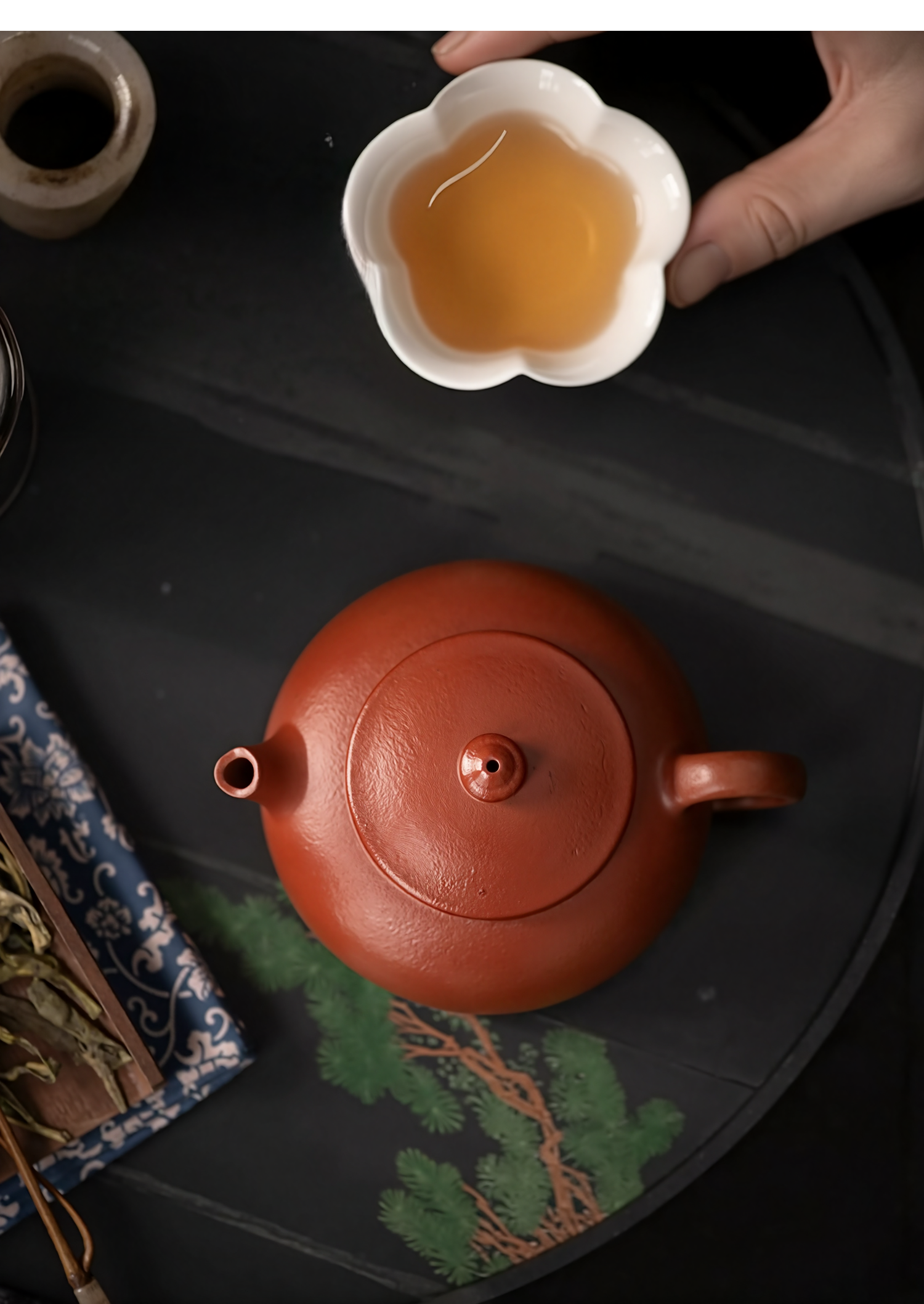 Red teapot with a white cup of tea on a dark surface