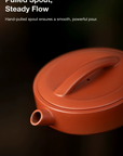 Red ceramic teapot with a pulled spout on a dark background