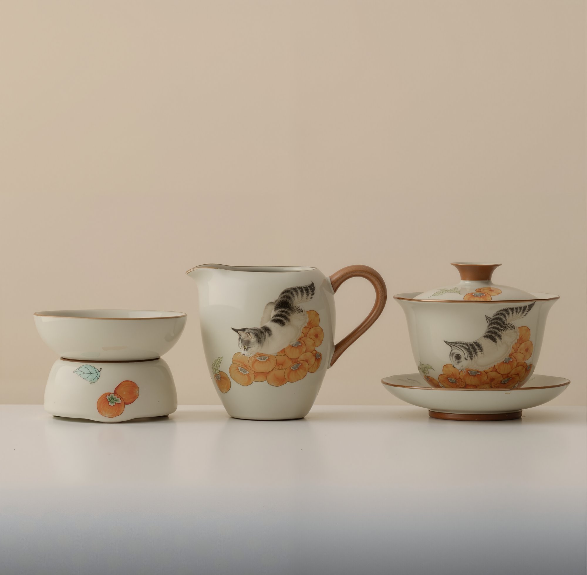 Three-piece ceramic tea set with cat and persimmon design, including gaiwan, fairness pitcher, and tea strainer, on a plain beige background.