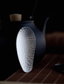 Hammered stainless steel tea scoop (8.3 × 3.5 cm) resting on a teapot lid, photographed against a dark background.