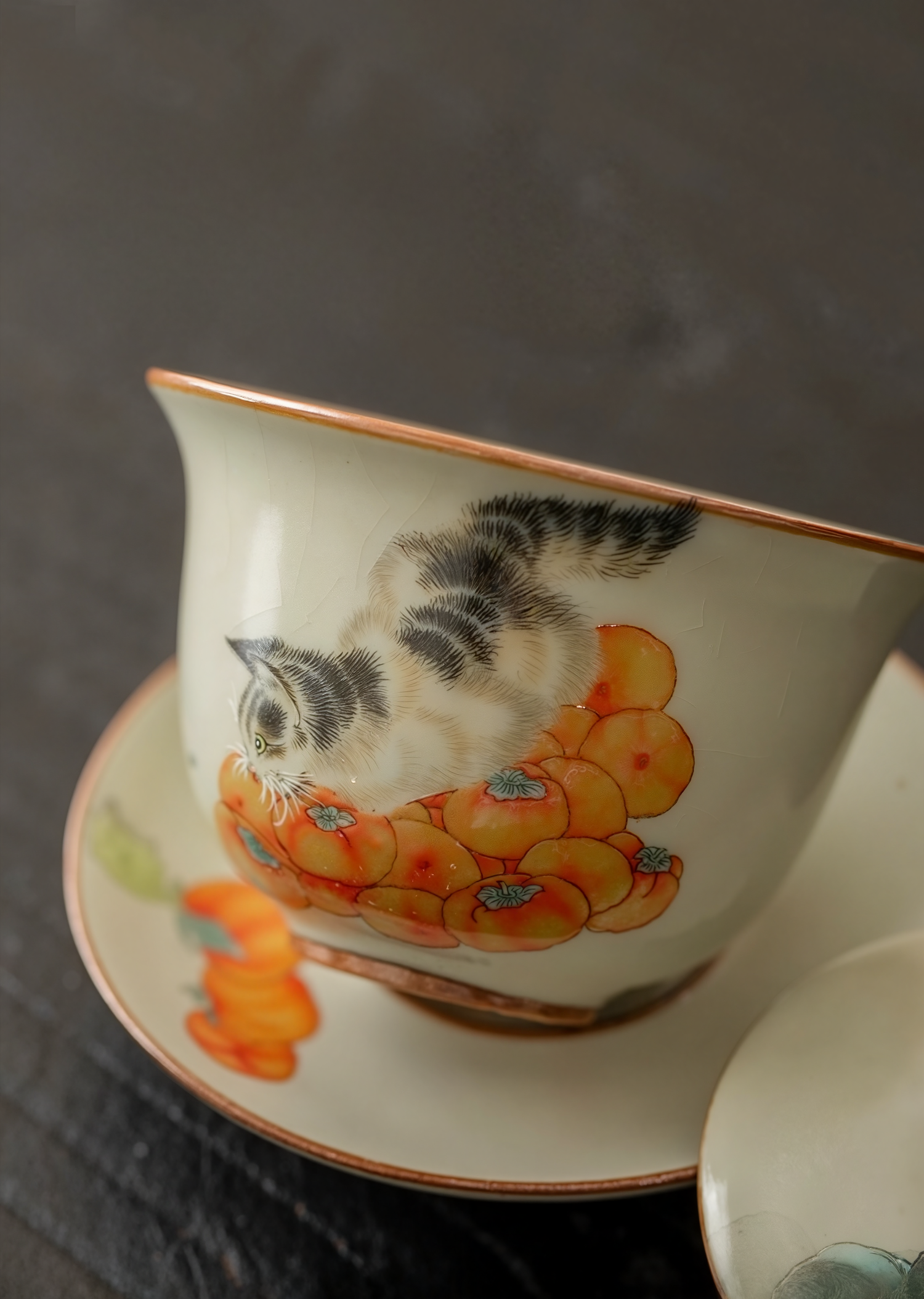 Porcelain gaiwan with hand-painted cat and persimmon design, placed on a dark background