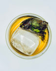 Top view of Lemon Still cold-brew DanCong oolong tea with ice, showing the unfolded whole-leaf blend inside the sachet.
