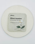 Silent Jasmine DanCong Oolong tea bag on a white ceramic plate, featuring minimalist floral packaging.