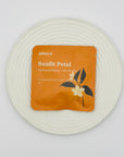 Sunlit Petal DanCong Oolong tea bag on a white textured plate, showcasing its citrus-toned bright floral blend.